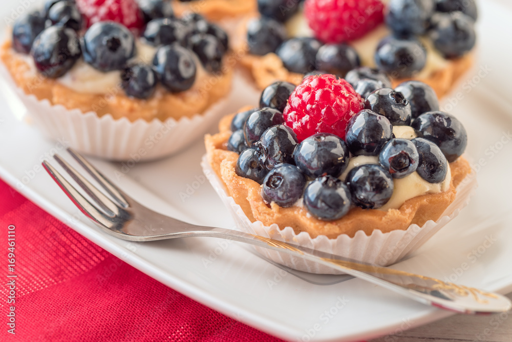 Tartlets with blueberries and raspberry on white plate. Tartlets with blueberries and raspberry on white plate.