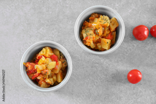 Two cocottes with vegetable stew on light background