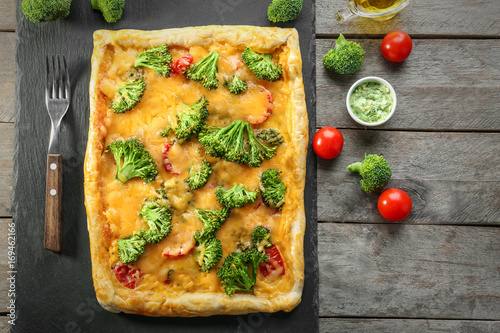 Traditional quiche with broccoli and cheese on wooden background