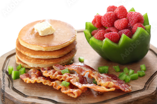 Tasty breakfast with pancakes, bacon and raspberry on wooden board