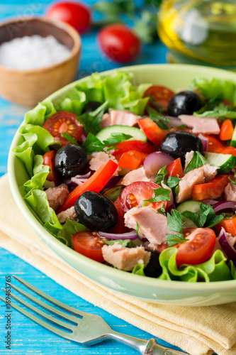 Salad with vegetables and tuna on rustic blue wooden table