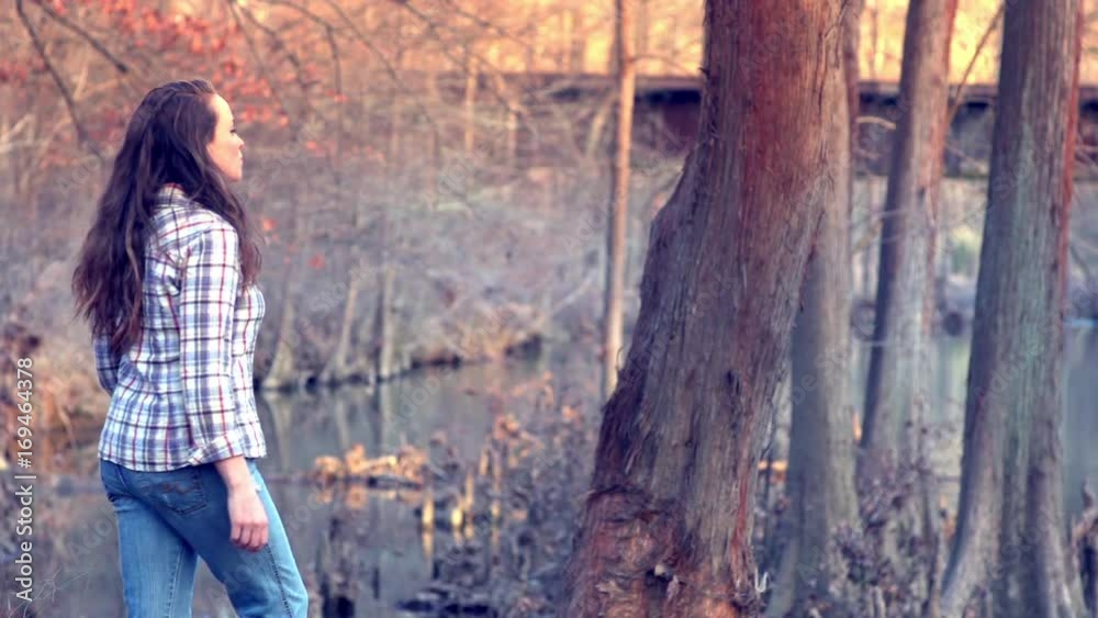 Woman approaches a beautiful creek and observes Woman approaches a beautiful creek and observes