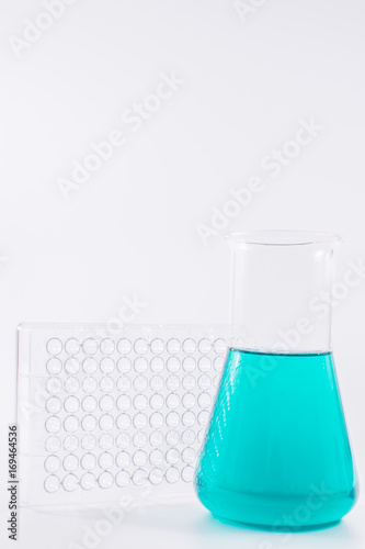  research, science and clinic background. 96 well micro plate and laboratory beakers with colorful liquids and reagents. 