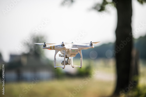 Fototapeta Naklejka Na Ścianę i Meble -  Quadrocopter drone with the camera. Copter flying against green blurred background.