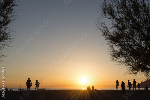 Silhouettes of people on the beach, watching the sunset