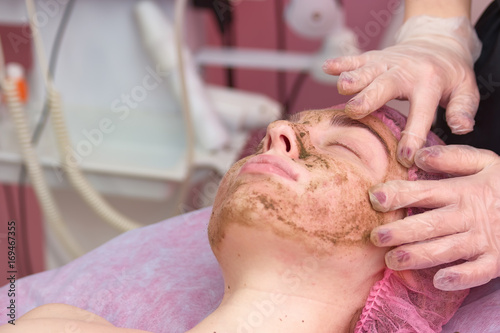 Coral face peeling. Cosmetician is applying facial mask. Organic cosmetics for delicate skin.