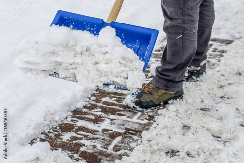 Man removing snow from the sidewalk after snowstorm