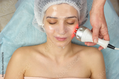 Radio frequency skin tightening device. Girl wearing hydrogel mask. Modern methods of skin treatment.