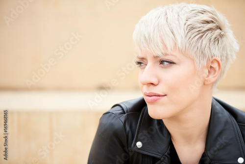 Short hair blondie in black leather jacket looking away.