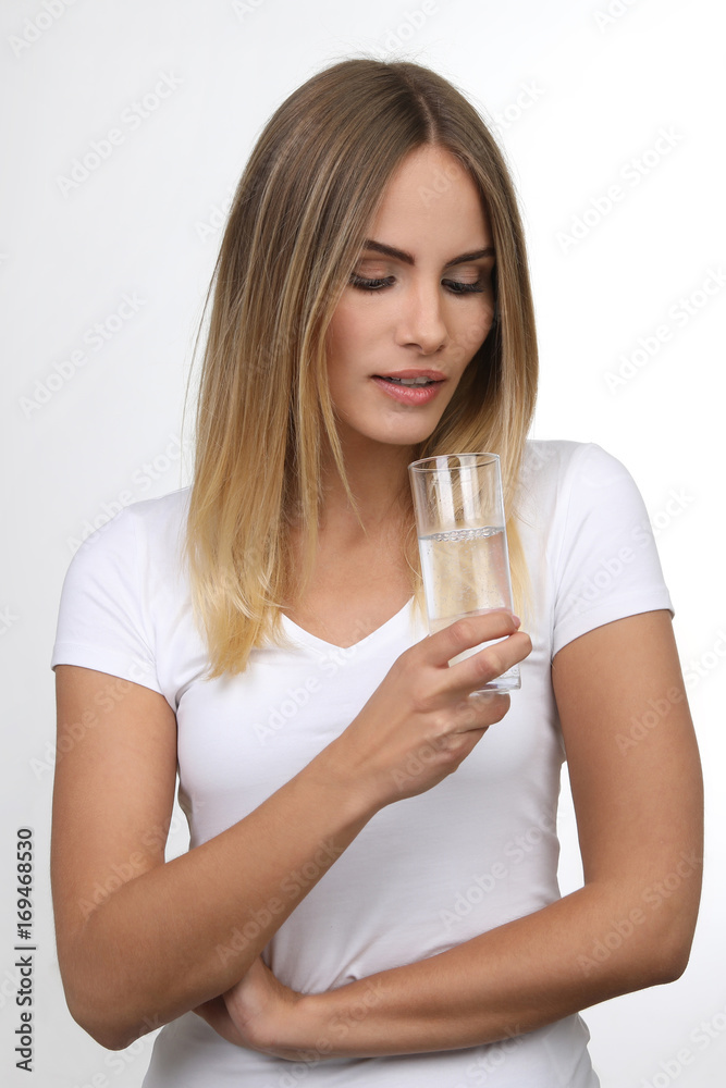 Hübsche blonde Frau schaut in ein Glas Wasser