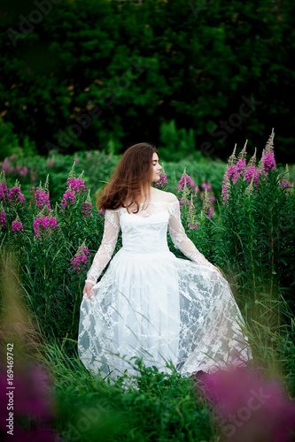 Beautiful bride in bright lace dress. In a field with Ivan-tea. Natural beauty, minimal makeup and loose hair. A child of nature