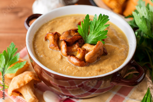 Mushroom cream soup with chanterelles and parsley on wooden background