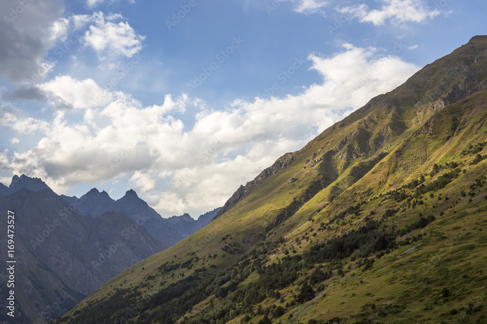 Горный пейзаж. Красивый вид на живописное ущелье, облачное небо над высокими горами. Природа Северного Кавказа