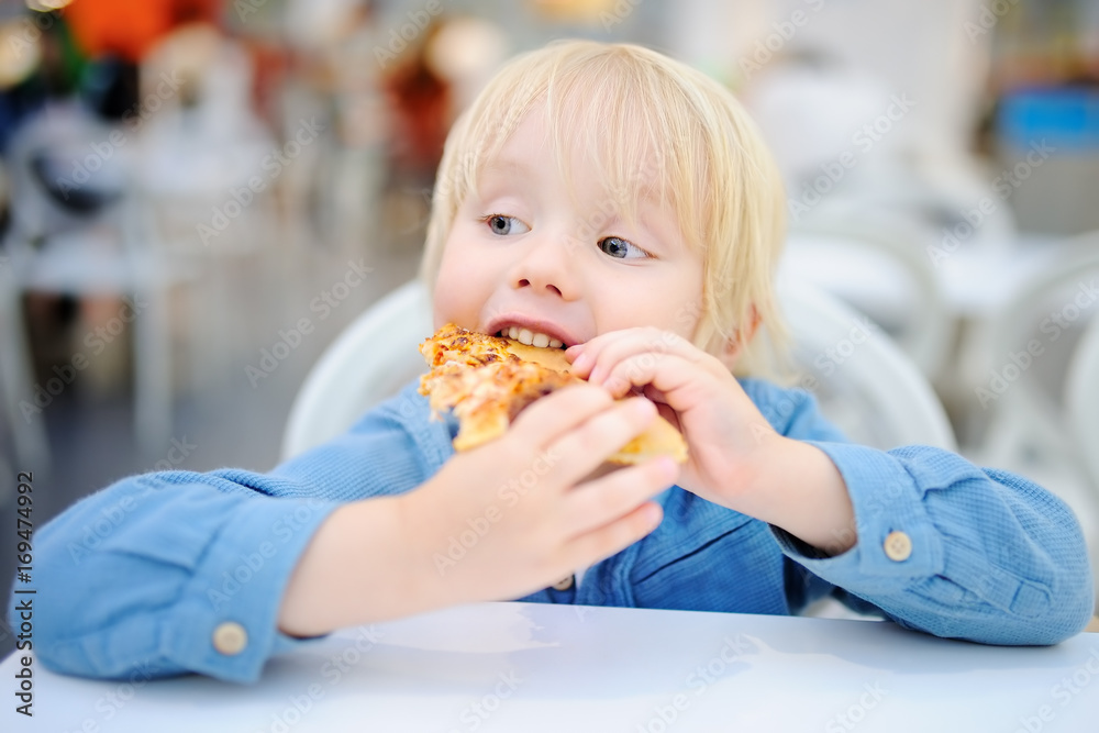 Cute blonde boy eating slice of pizza at fast food restaurant Cute blonde boy eating slice of pizza at fast food restaurant