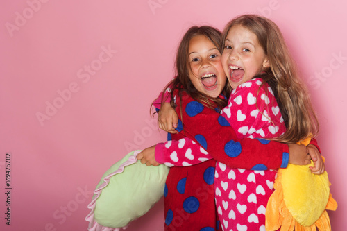 Girls in colorful polka dotted pajamas hold funny pillows