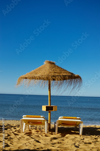 Sunny sky and chairs with parasol on the beautiful beach of Portugal