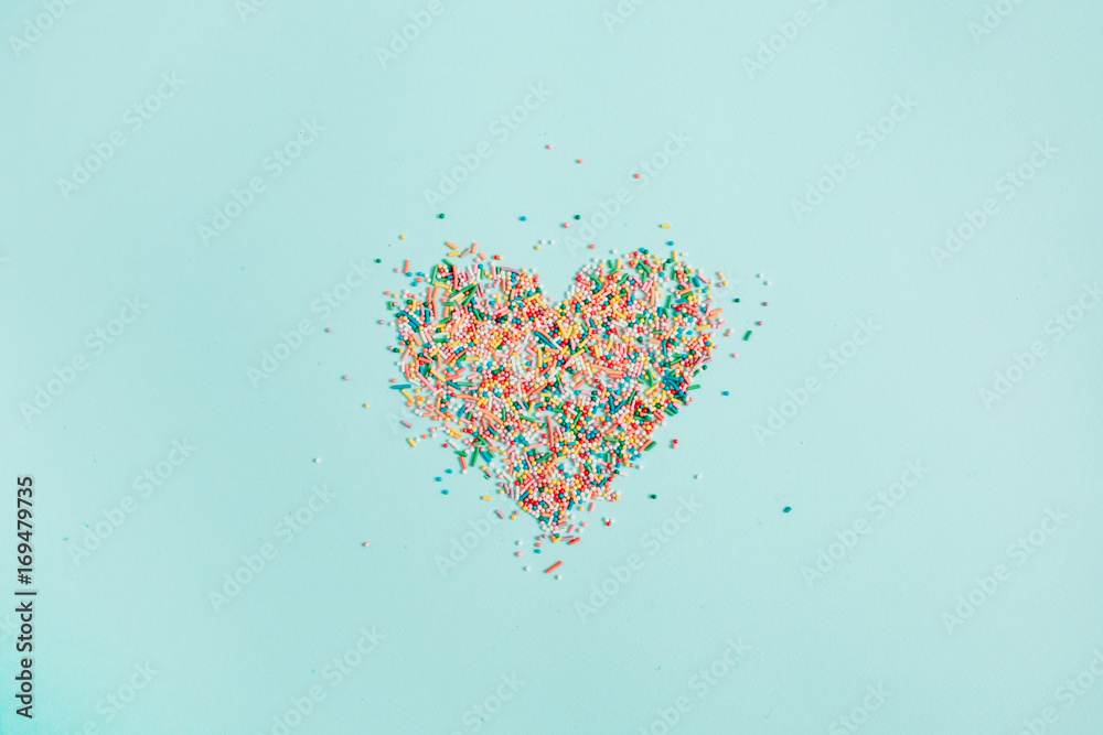 Colorful heart symbol made of confetti on blue background. Flat lay, top view. - obrazy, fototapety, plakaty 