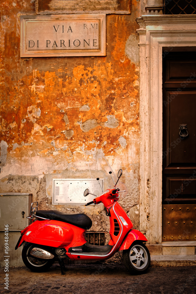 Naklejka premium Typowa scena z czerwonym skuterem na wąskiej uliczce w centrum Rzymu
