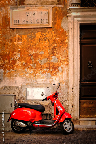 Typical scene with a red scooter on a narrow central Rome street