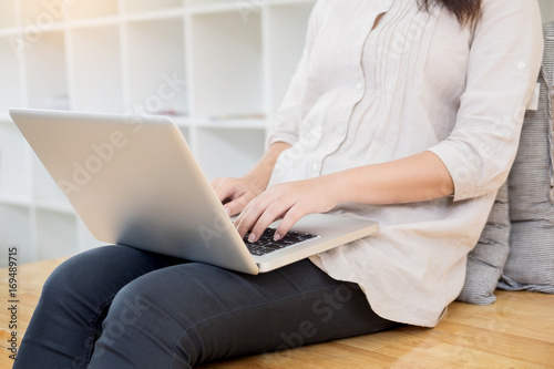 Young woman sitting on floor with laptop in library, education and technology concept.