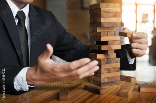 Planning, risk and wealth strategy in business concept, businessman and insurance gambling placing wooden block on a tower