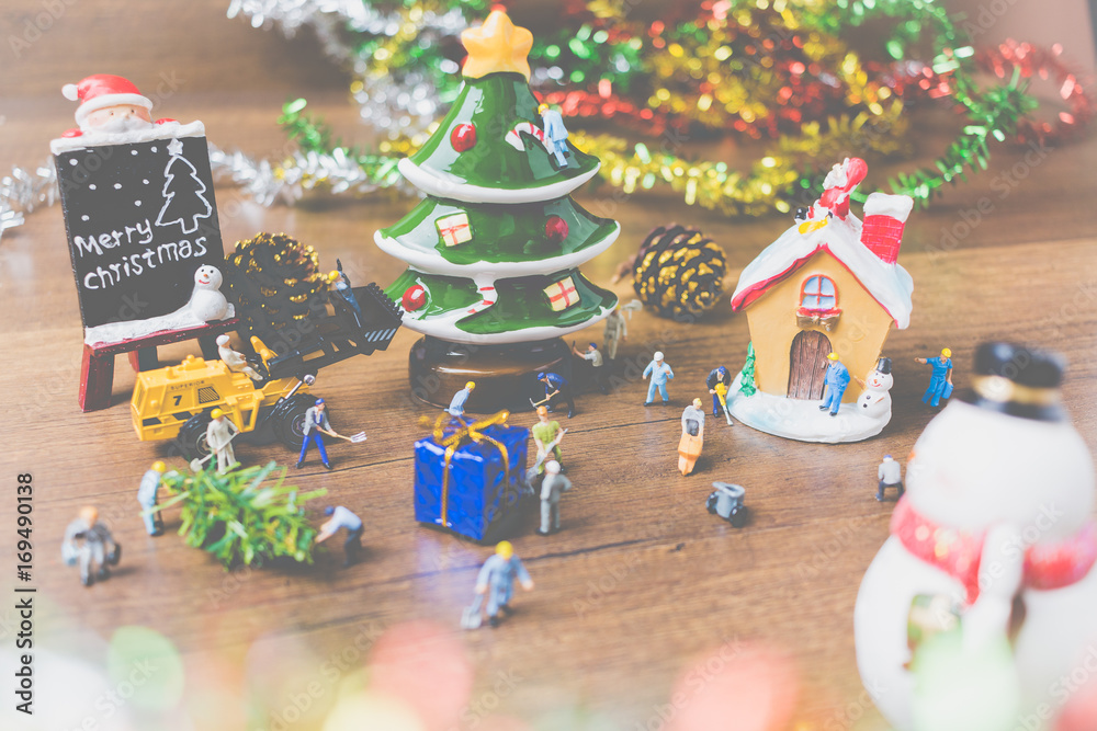 Creative concept with miniature people creating Christmas decorations on a wooden background.