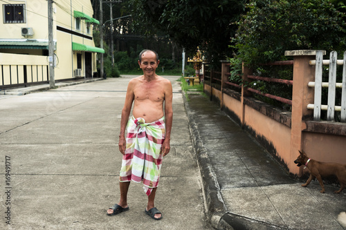 Old man with loincloth standing on public street. Rural scene