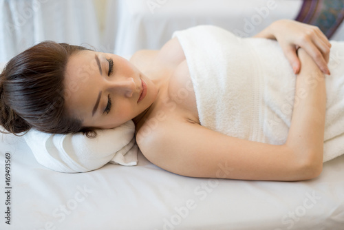 Beautiful smiling woman with flowers resting in the spa before massage.