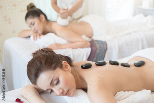 Young beautiful woman getting hot stone massage in spa salon.