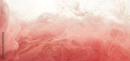 Ink swirl in water isolated on white background. The paint in the water. Soft dissemination a droplets of pink ink in water close-up. Abstract background. Explosion of splashes yellow acrylic ink.