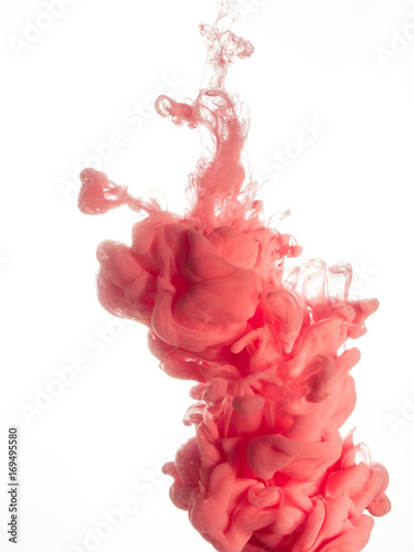 Ink swirl in water isolated on white background. The paint in the water. Soft dissemination a droplets of pink ink in water close-up. Abstract background. Explosion of splashes yellow acrylic ink.