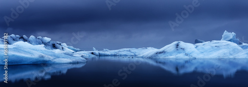 Scenic view of glacier in lake against cloudy sky