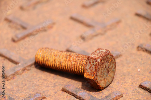 Rusty metal bolt Lay down on the steel plate floor in brown color with rusty iron. rust is a reddish or yellowish-brown flaky coating of iron oxide that is formed on iron by oxidation.