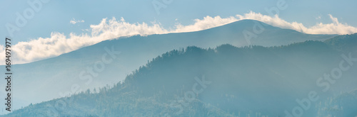 Fototapeta clouds rising behind the blue mountain