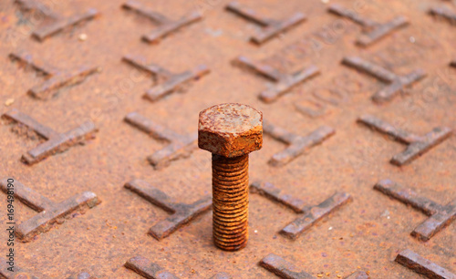 Rusty metal bolt put on the steel plate floor in brown color with rusty iron. rust is a reddish or yellowish-brown flaky coating of iron oxide that is formed on iron by oxidation.