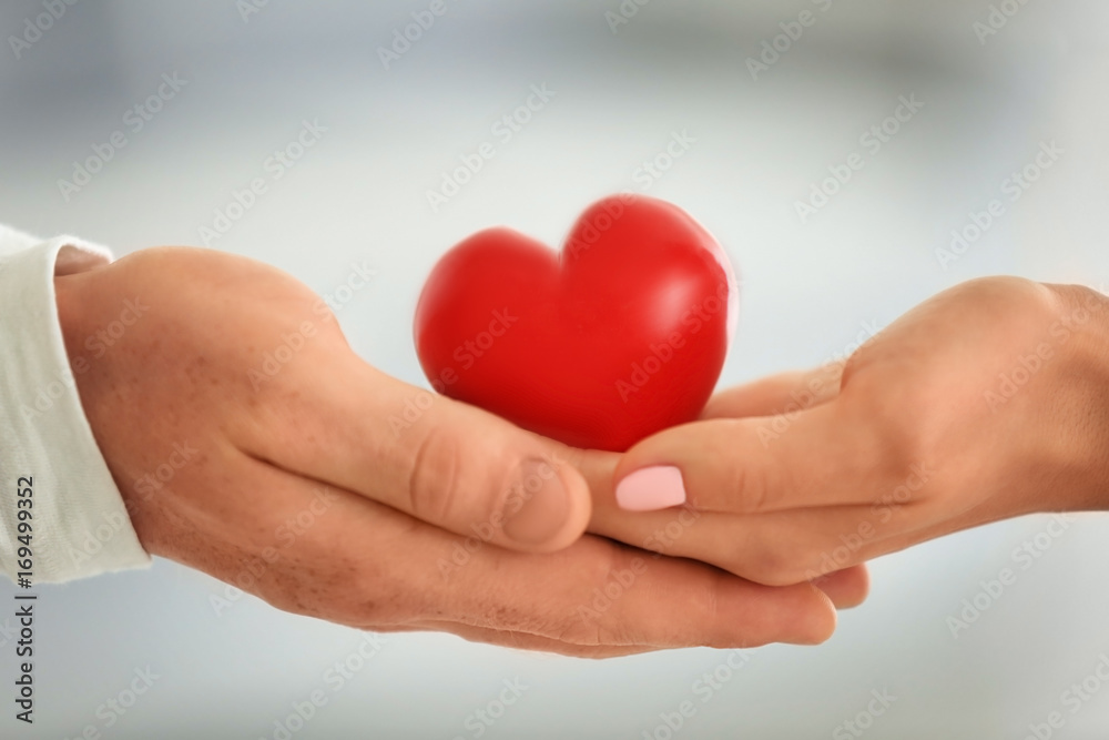 Lovely couple holding small red heart, closeup