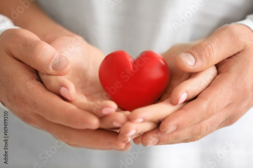 Lovely couple holding small red heart, closeup