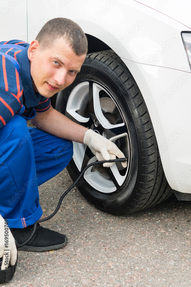 the master of tire fitting inflates the wheel of the car with a pump