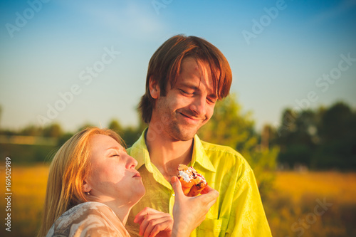Honeymoon couple romantic eatind pie in love at field and trees sunset. Newlywed happy young couple embracing enjoying nature sunset during travel holidays vacation getaway. Caucasian man,woman. photo