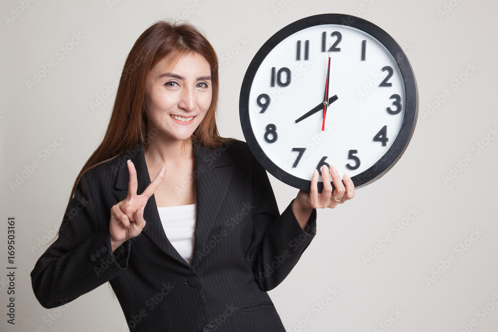 Young Asian business woman show victory sign with a clock. Young Asian business woman show victory sign with a clock.