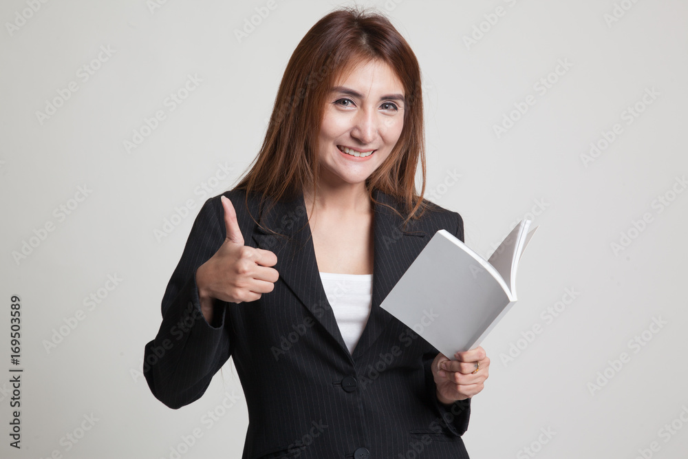 Young Asian woman thumbs up with a book. Young Asian woman thumbs up with a book.