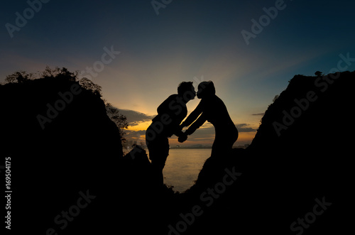 Silhouette of happy lover holding each other on the mountain over the sea and twilight sky, valentine lover concept