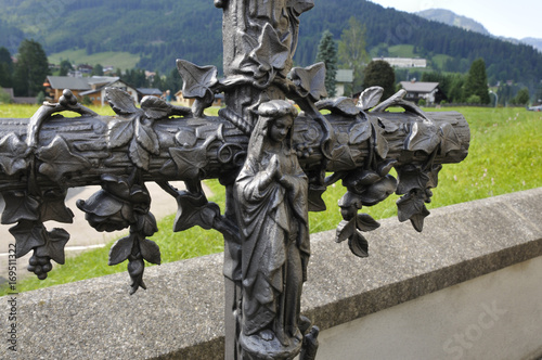 grabkreuz mit madonna an der friedhofsmauer in riezlern, kleinwalsertal photo