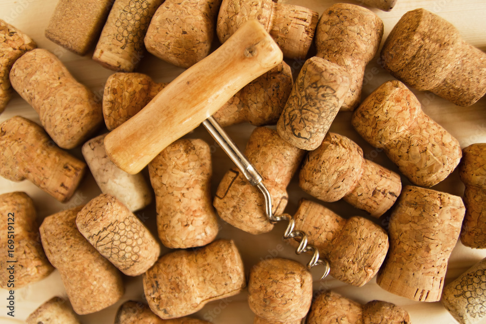 Wine corks and corkscrew on the wooden background, top view.