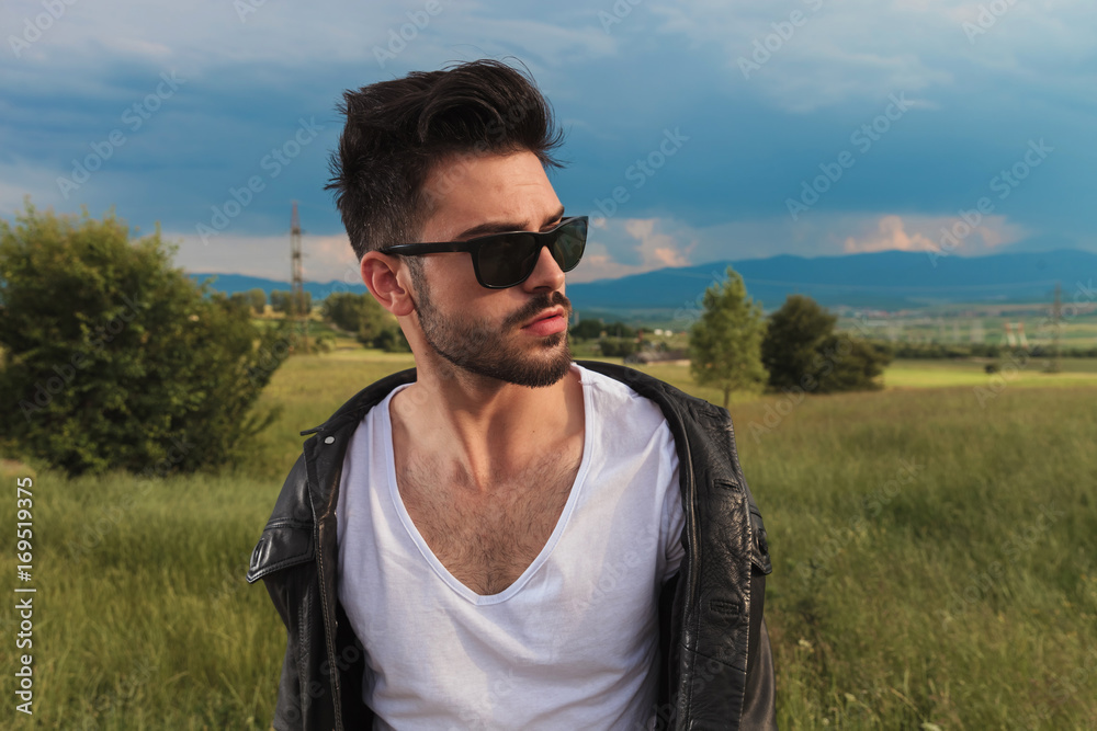 man wearing sunglasses and leather jacket and looks away