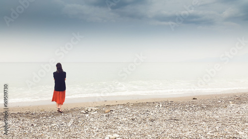 Young woman walking alone in barefoot at the shore