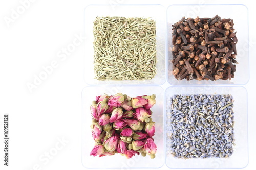 four bowls of dry green rosemary, dry brown cloves ,dry pink roses and  dry violet lavanders on white background , Fragrant ingredients of meal  and tea , the ingredients background photo