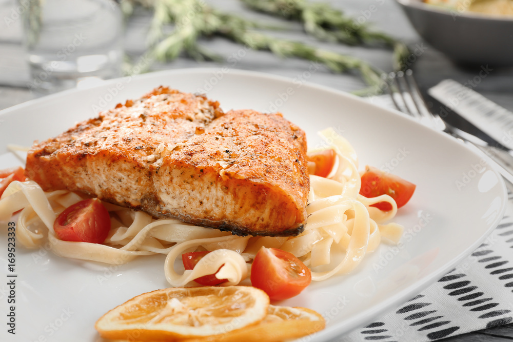 Plate with pasta, salmon, cherry tomatoes and sliced lemon, closeup Plate with pasta, salmon, cherry tomatoes and sliced lemon, closeup