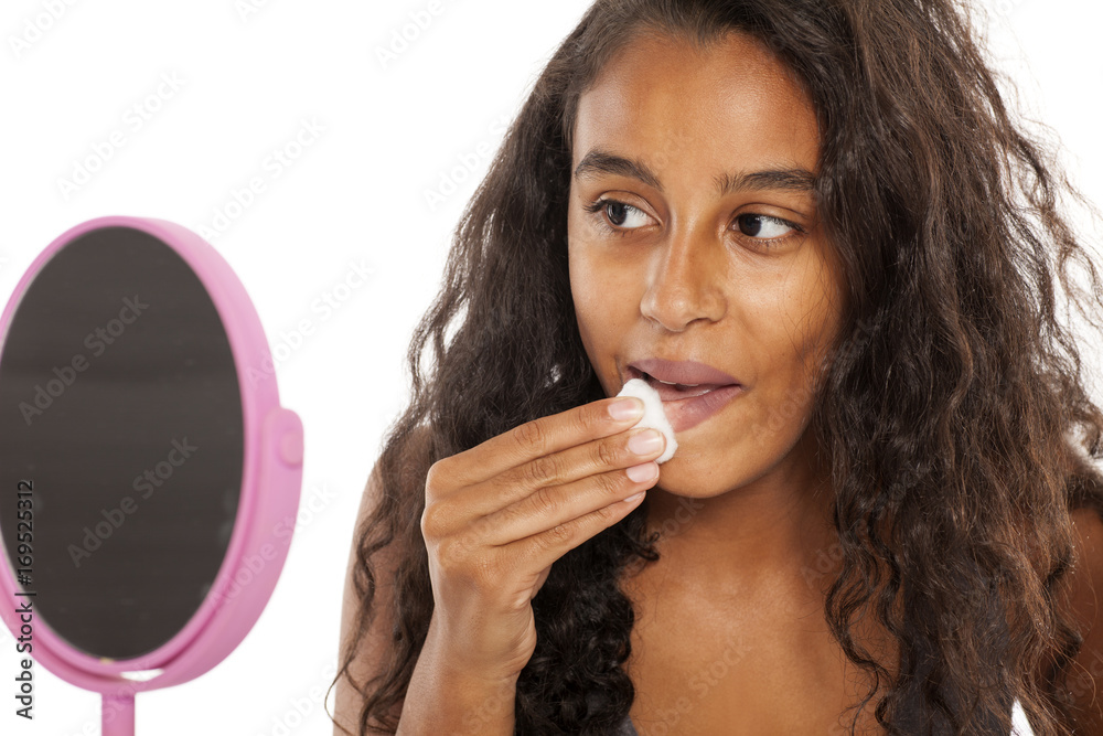 A young dark-skin girl remove her makeup on white background A young dark-skin girl remove her makeup on white background