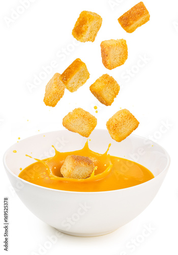 croutons falling into a soup bowl isolated on white photo